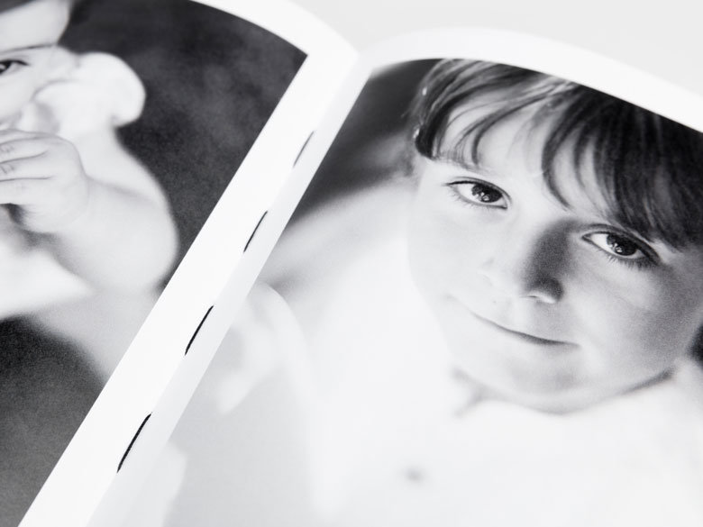 Open magazine with black and white photos Open softcover book with black-and-white photographs of children printed on adjacent pages.