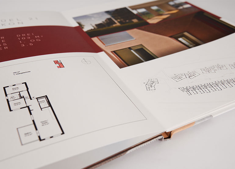 Architectural Project Brochure with Floor Plans Open hardcover book with architectural floor plans and photographs printed on the pages, showing detailed layouts and building images.