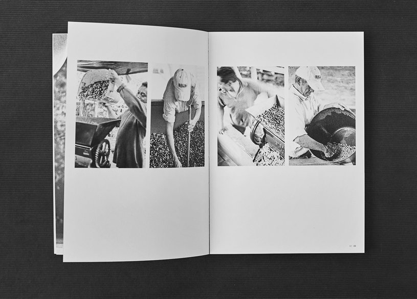Geöffneter Bildband mit Schwarzweiss-Fotografien Aufgeschlagene Broschüre mit vier schwarz-weiss Fotos, die Menschen bei der Verarbeitung oder Kontrolle von Kaffeebohnen zeigen. Die Broschüre liegt auf einer dunklen Oberfläche.
