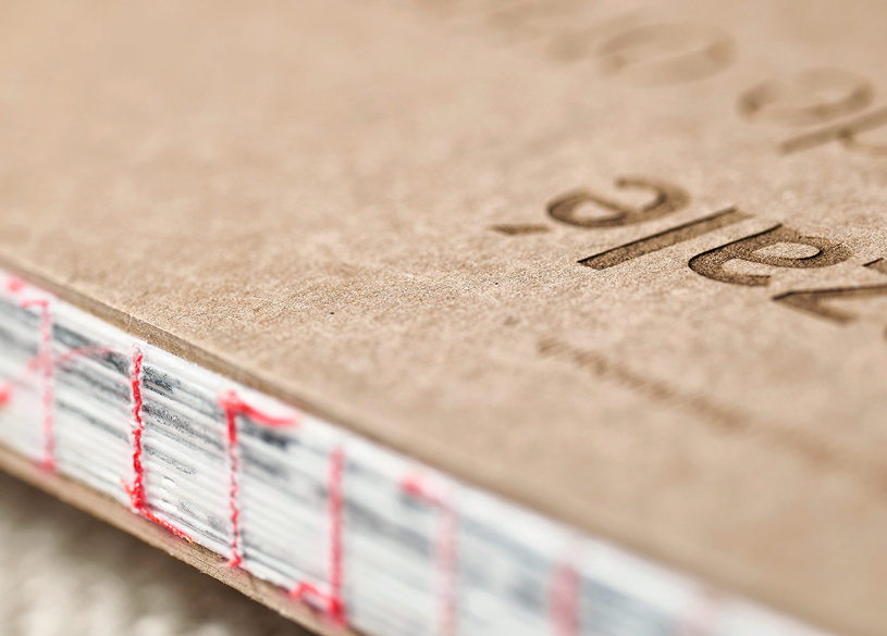 Offener Fadenheftung Umschlag aus Kraftpapier Nahaufnahme eines Buchrückens mit Fadenheftung und Buchdeckeln aus braunem Kraftpapier, teilweise sichtbarer Schrift auf dem Cover.