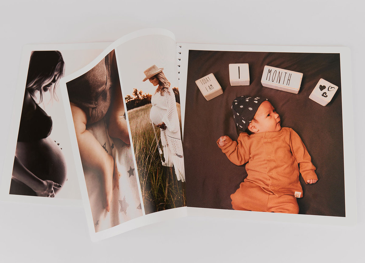Livre photo avec pages ouvertes montrant des photographies d’une femme enceinte et d’un bébé allongé à côté de cubes indiquant « 1 month ». Les images sont imprimées sur papier brillant avec une reliure spirale blanche.
