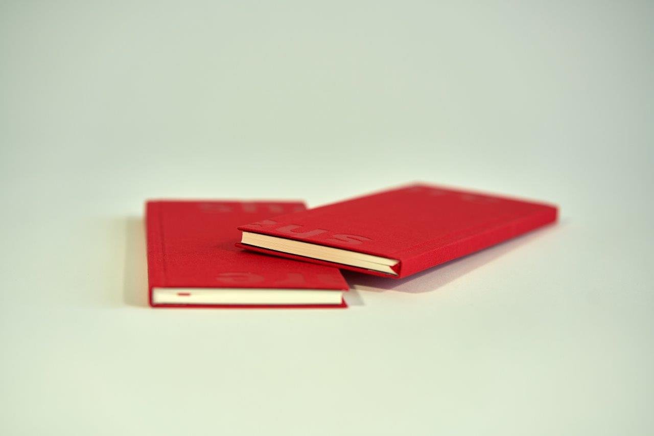 Red hardcover notebooks with visible spine binding BNB 2019 - The Sharing Book