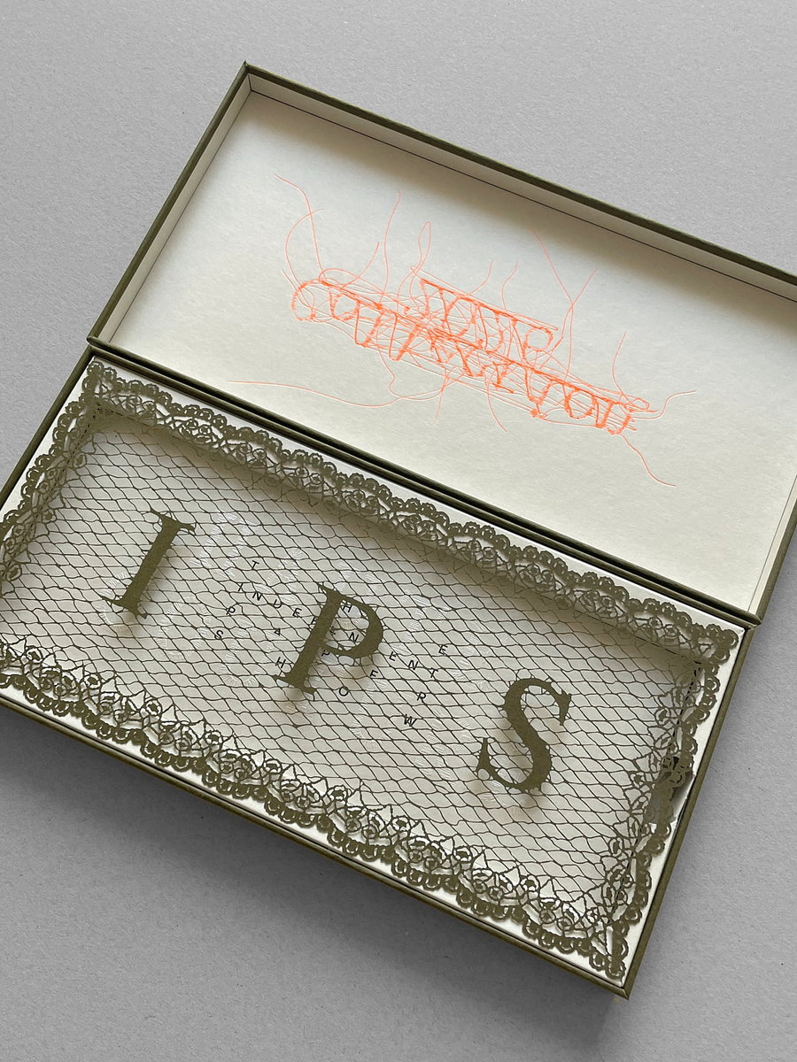 Boîte avec lettres décoratives et filet dentelle Boîte beige ouverte avec du papier translucide orné d’une bordure en dentelle, contenant trois grandes lettres découpées « I », « P » et « S ». Le couvercle intérieur présente un motif en fil rouge semblant abstrait.